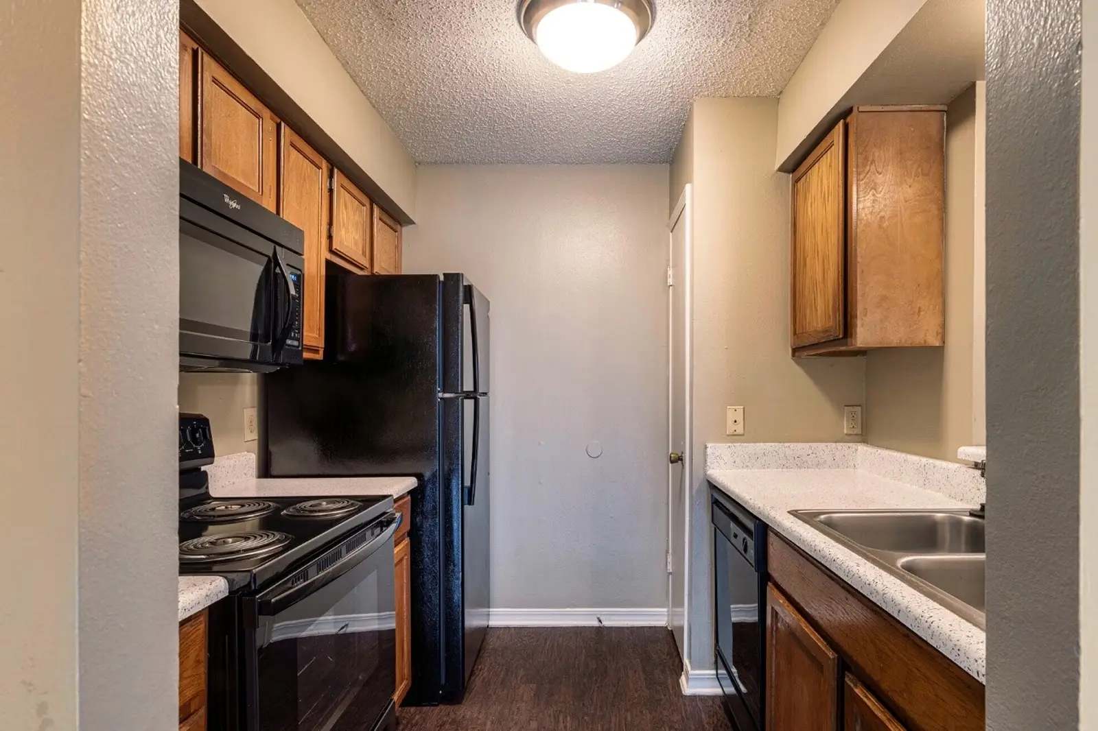 Compact kitchen with black appliances and wooden cabinets.