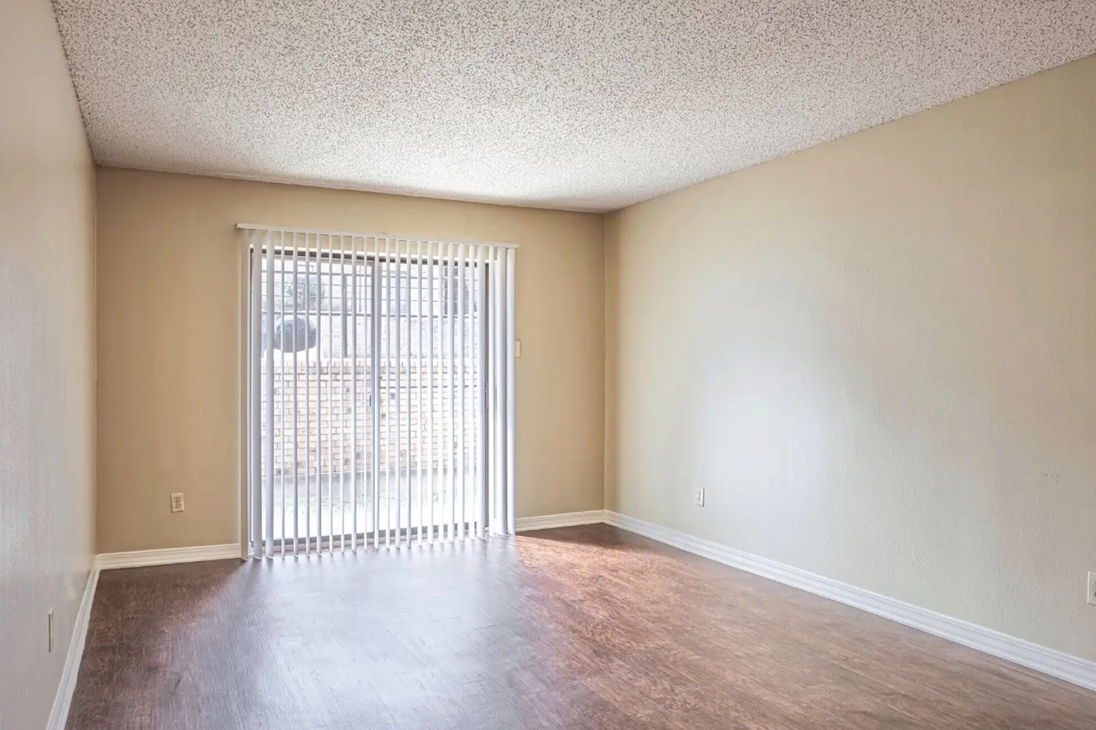 Empty room with wood-style flooring and sliding glass door.