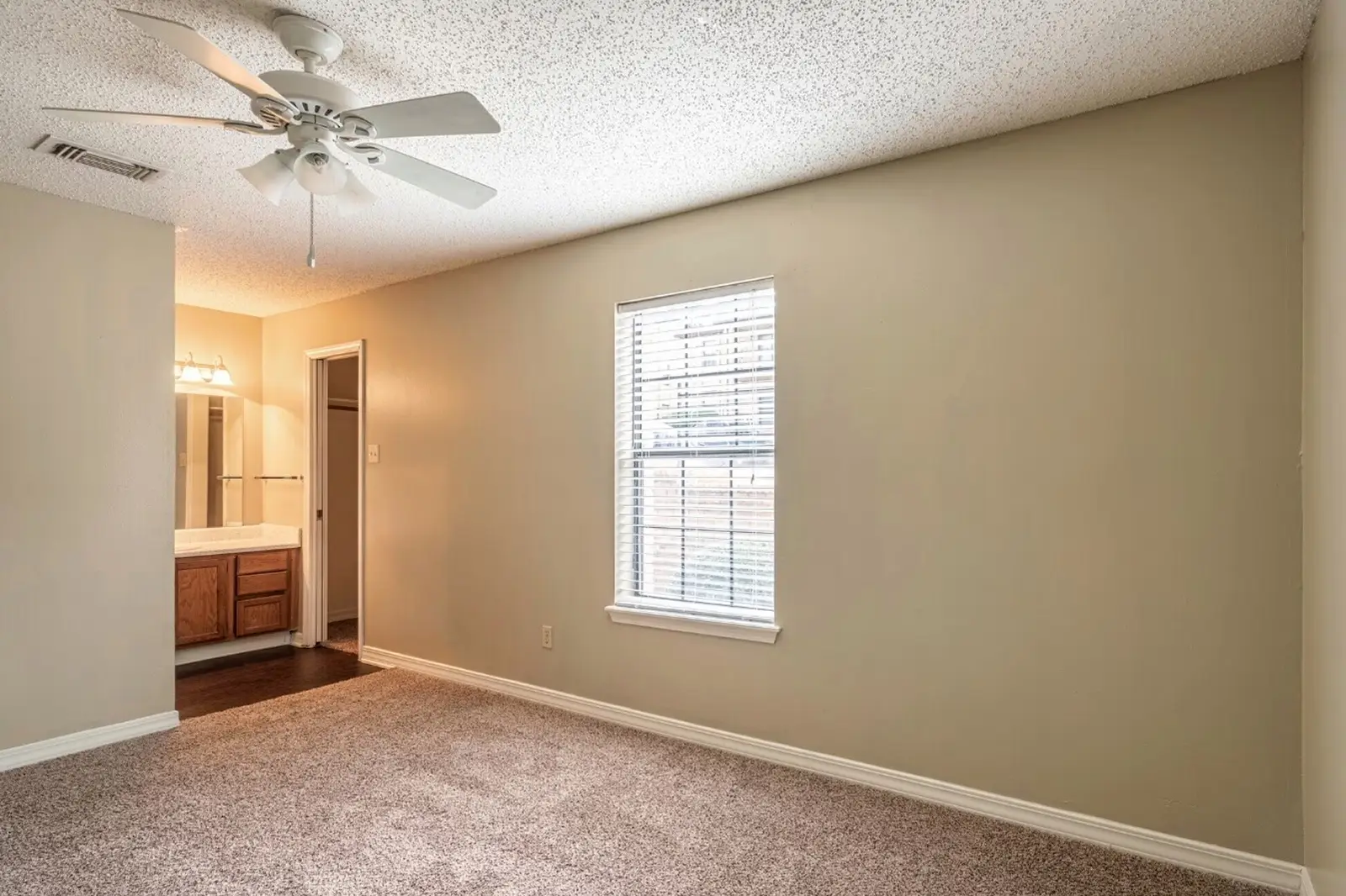 Bedroom with carpet, ceiling fan, and private bathroom vanity.