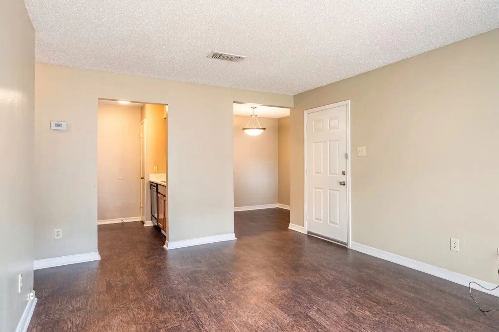 Open living space with wood-style floors and view into kitchen.