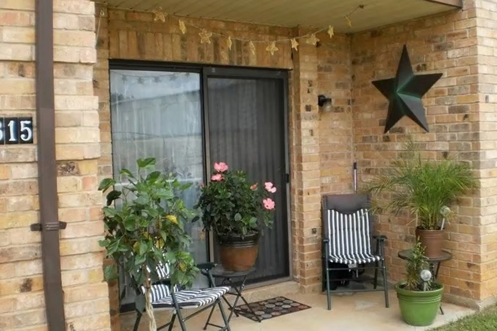 Cozy apartment patio with plants and striped chairs.