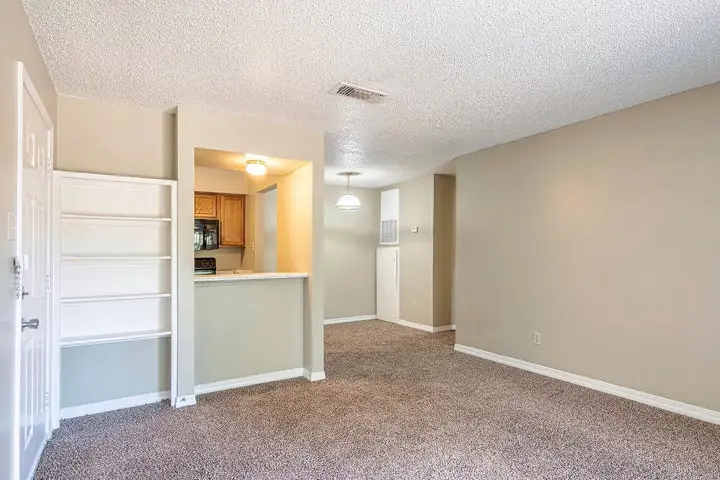 Spacious living area with carpet and open view into kitchen.
