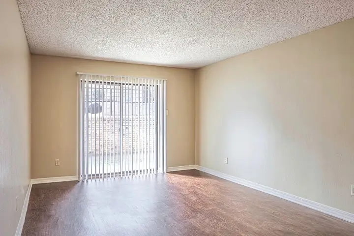 Empty room with wood-style flooring and sliding glass door.