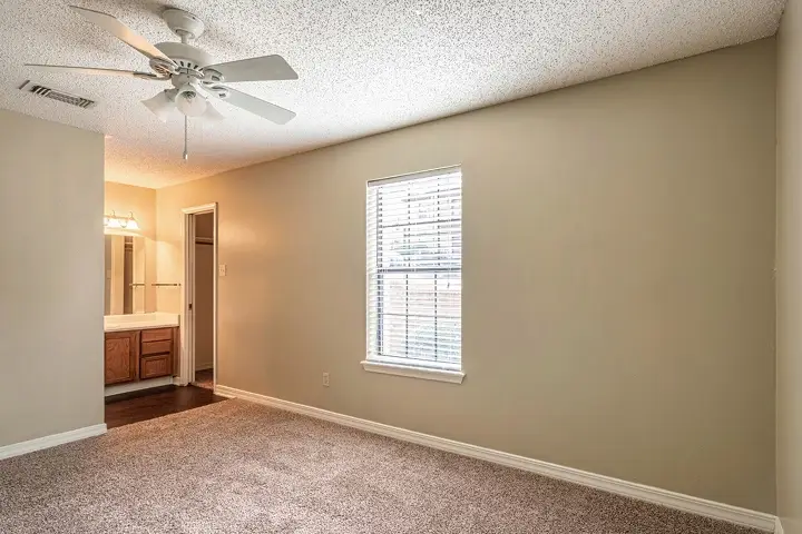 Bedroom with carpet, ceiling fan, and private bathroom vanity.