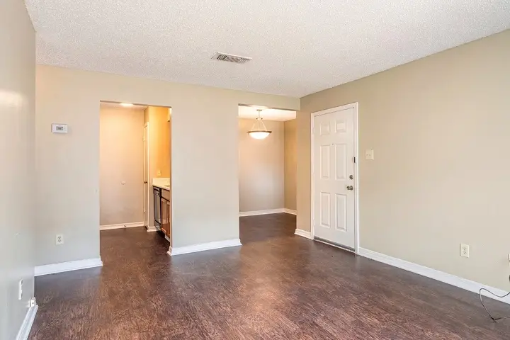 Open living space with wood-style floors and view into kitchen.