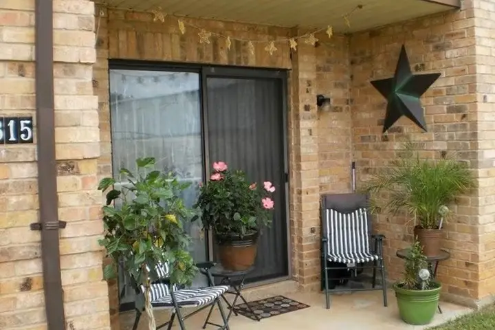 Cozy apartment patio with plants and striped chairs.